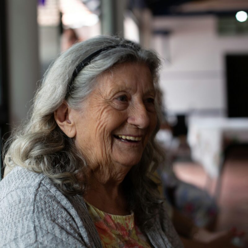 Une dame souriante dans un EHPAD, exprimant de la joie et de la bienveillance.