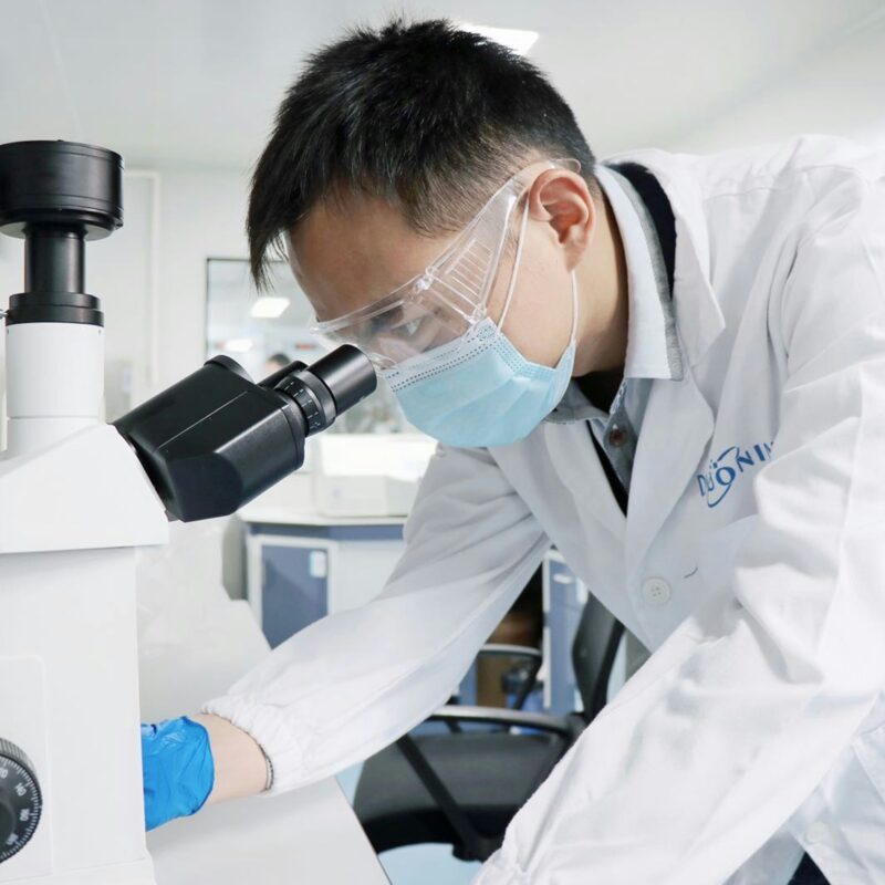 Un homme en blouse regardant dans un microscope