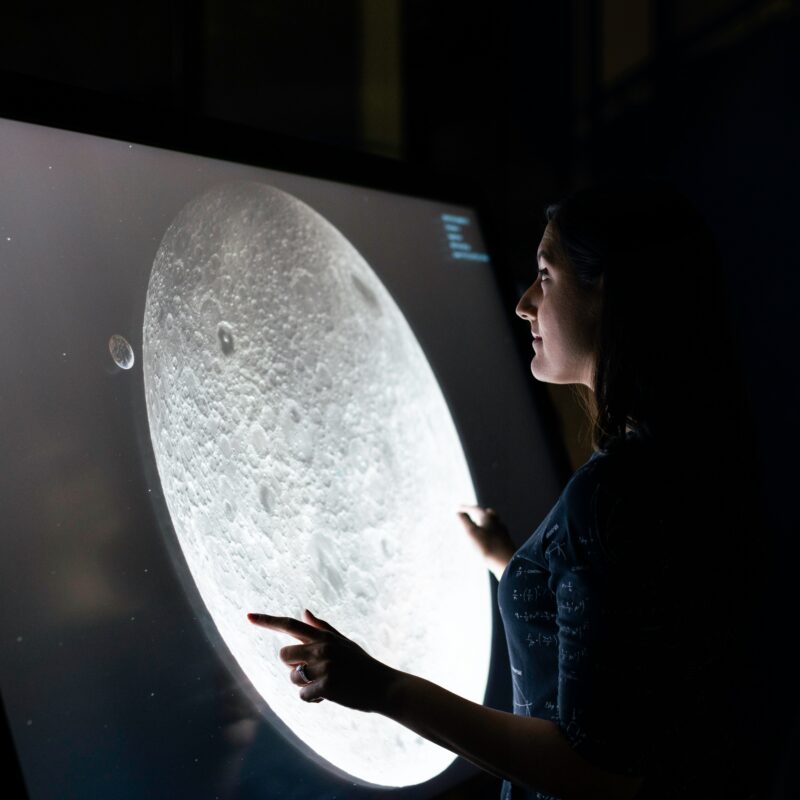 Femme touchant un écran représentant une lune
